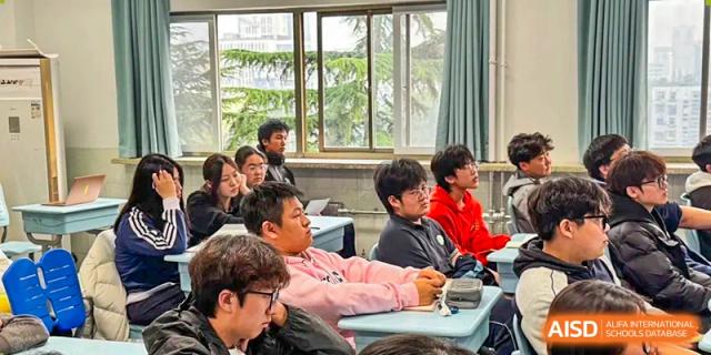 A classroom full of students in colorful winter jackets listens intently to their teacher during an afternoon lesson at XuZhou No.3 Middle School.