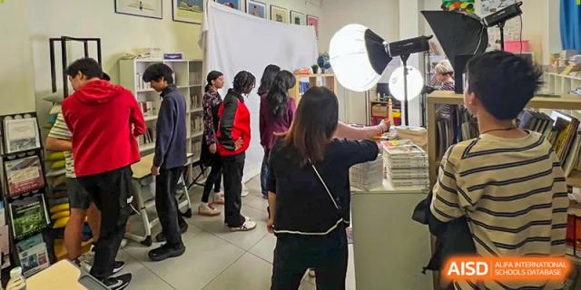 Students and staff gather in a library setting near professional studio lighting equipment for a photoshoot at École Française Internationale de Canton(EFIC)