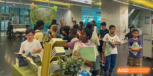 A group of students gather in a library aisle to browse books and socialize between their daily classes at École Française Internationale de Canton(EFIC)