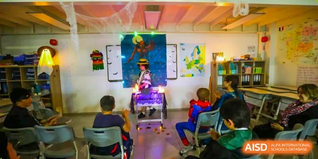 A student performs on a small stage decorated with maps and purple lights for a classroom presentation at École Française Internationale de Canton(EFIC)