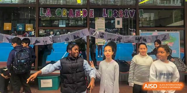 Two students smile while standing in a hallway decorated with student artwork and colorful school banners at École Française Internationale de Canton(EFIC)