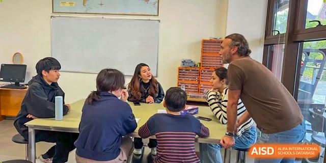 A female teacher leads a collaborative lesson with a group of students seated at a round table in class at École Française Internationale de Canton(EFIC)