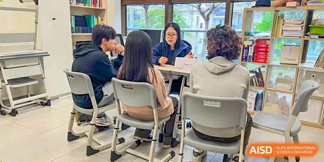 A teacher and students sit at a table for a small group learning session in a bright and airy schoolroom at École Française Internationale de Canton(EFIC)