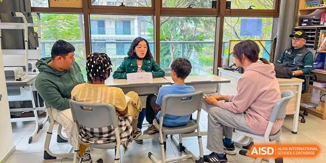 A teacher sits at a desk to assist a student with their studies in a modern and bright classroom environment at École Française Internationale de Canton(EFIC)