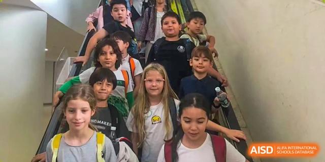 A group of young students gather together for a casual group photo inside a school building at École Française Internationale de Canton(EFIC)