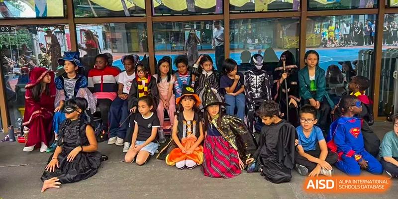 A large group of students in themed costumes pose together outdoors for a festive group portrait at École Française Internationale de Canton(EFIC)