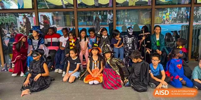 A large group of students in themed costumes pose together outdoors for a festive group portrait at École Française Internationale de Canton(EFIC)