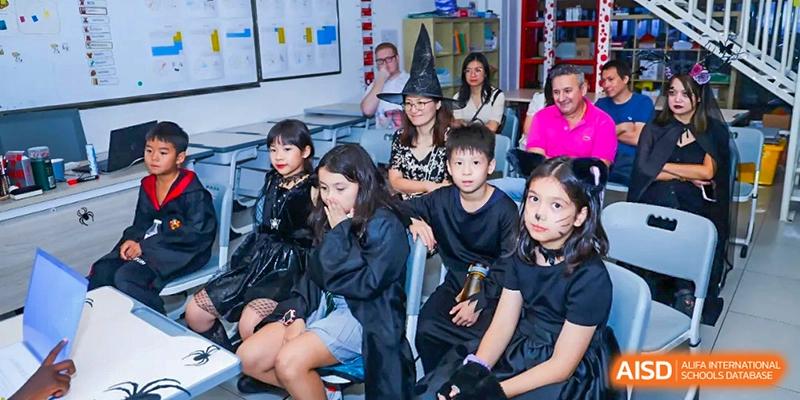 A group of students in dark costumes sit attentively in a classroom during a themed school activity at École Française Internationale de Canton(EFIC)