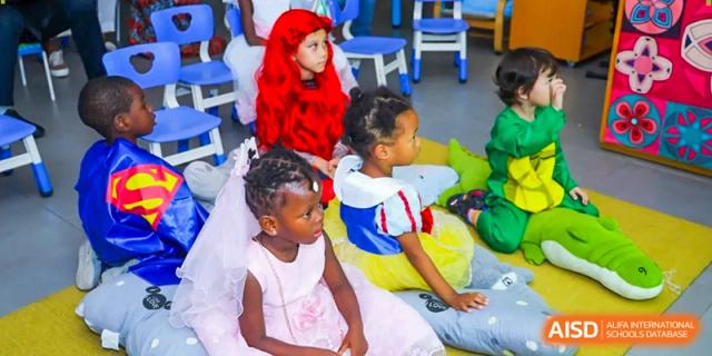 Young girls dressed as princesses and characters sit together on a blue mat during a school costume day at École Française Internationale de Canton(EFIC)