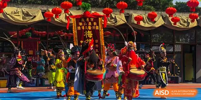 Performers in elaborate traditional costumes play drums during a cultural festival on the school grounds at École Française Internationale de Canton(EFIC)