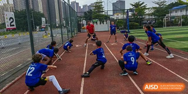 Students participate in an outdoor training drill on a red track while an instructor leads the session at École Française Internationale de Canton(EFIC)