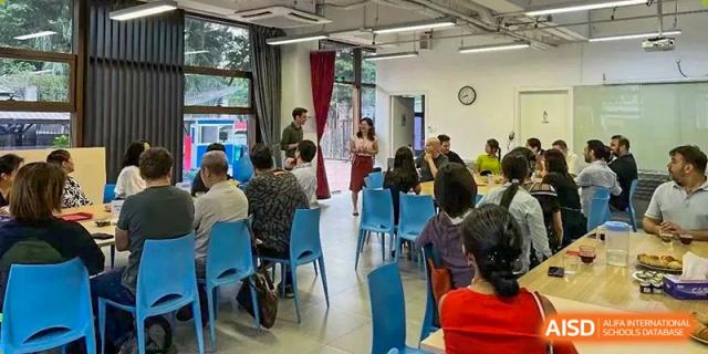 Staff and parents sit at blue chairs in a bright room during an informative school meeting or presentation at École Française Internationale de Canton(EFIC)