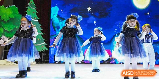 Two young girls in sparkling blue tutus perform a dance routine on a stage with a starry backdrop at Beijing International Bilingual Academy Guiyang.