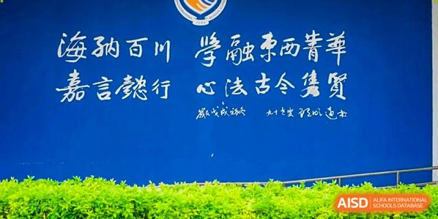 A blue wall on campus displays traditional white calligraphy, reflecting the cultural curriculum at Beijing International Bilingual Academy Guiyang.