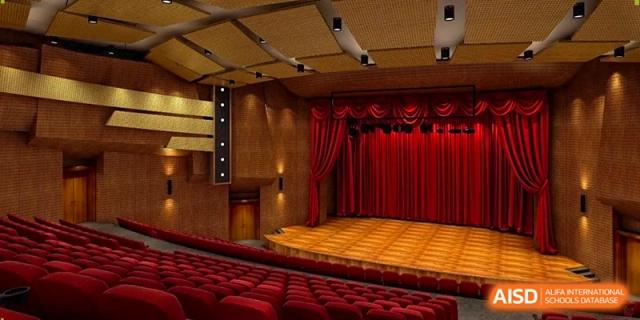 A formal auditorium features rows of red velvet seats facing a large stage with red curtains at Beijing International Bilingual Academy Guiyang.