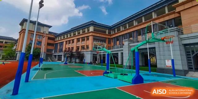 An outdoor blue and green basketball court sits ready for play next to the academic buildings at Beijing International Bilingual Academy Guiyang.