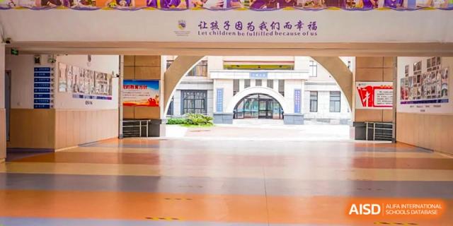A bright, wide corridor leads to an arched entryway inside the modern school facility at Beijing International Bilingual Academy Guiyang.