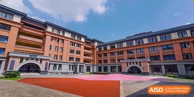 A courtyard paved with pink and grey tiles sits between the multi-story academic wings at Beijing International Bilingual Academy Guiyang.
