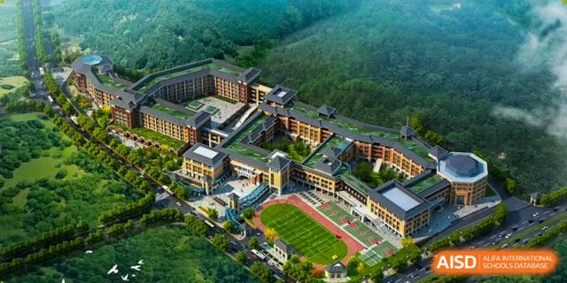 An aerial view shows the expansive school campus nestled within a green, hilly landscape at Beijing International Bilingual Academy Guiyang.