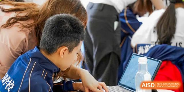 A young boy uses a laptop as he participates in a STEM-focused activity in the classroom at Beijing International Bilingual Academy Guiyang.
