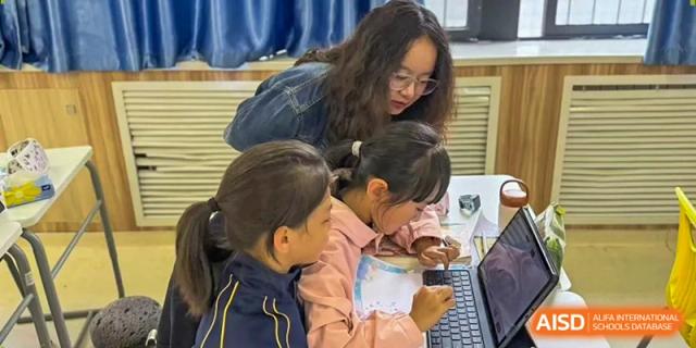 Two young students work closely together on a project in a well-lit, modern classroom at Beijing International Bilingual Academy Guiyang.