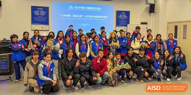 A large group of students and teachers pose for a commemorative photo in front of a blue banner at Beijing International Bilingual Academy Guiyang.