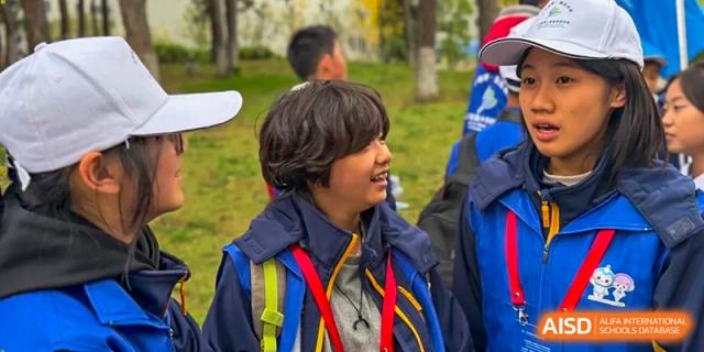 A student with wavy hair looks off-camera while wearing a blue and yellow school jacket at Beijing International Bilingual Academy Guiyang.