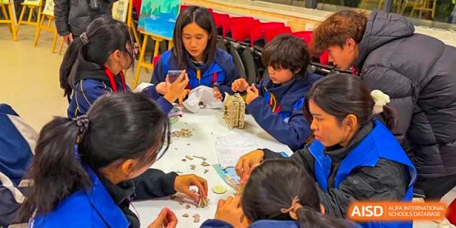 A close-up of students working together on a project spread out across a classroom table at Beijing International Bilingual Academy Guiyang.