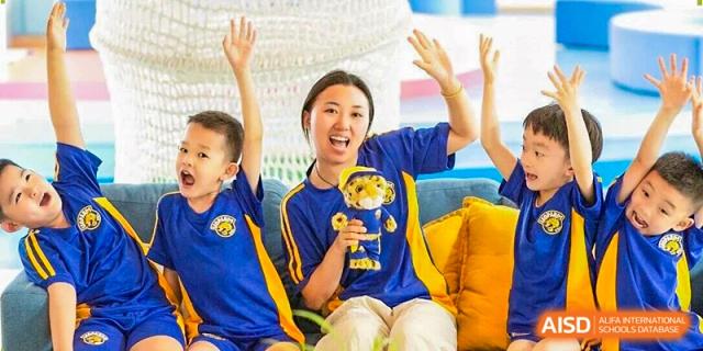 A student smiles brightly while holding a small gold trophy during a school celebration at Beijing International Bilingual Academy Guiyang.