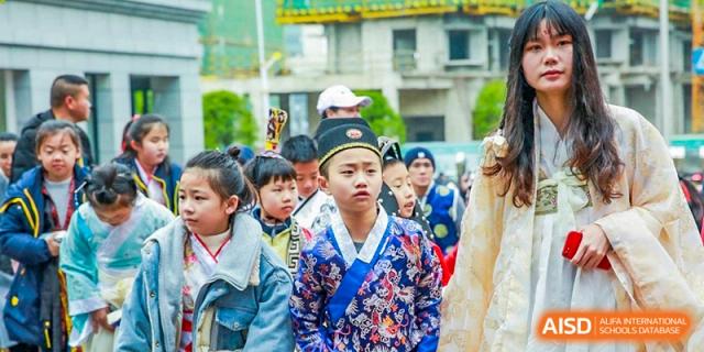 Students dressed in traditional blue and red patterned robes participate in a cultural ceremony at Beijing International Bilingual Academy Guiyang.