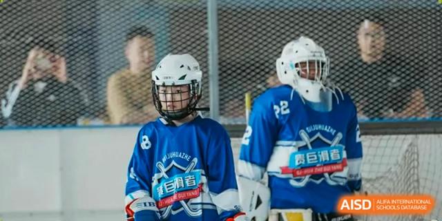 A young athlete in a blue hockey jersey and white helmet stands ready on the rink at Beijing International Bilingual Academy Guiyang.