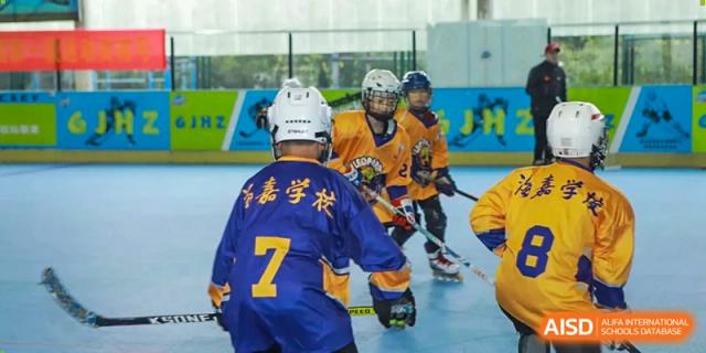 Teammates in purple and orange jerseys coordinate their play during an indoor hockey session at Beijing International Bilingual Academy Guiyang.