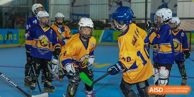Young athletes in vibrant team jerseys engage in a competitive hockey game at Beijing International Bilingual Academy Guiyang.