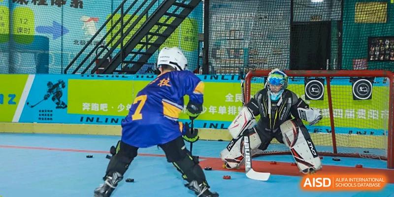 A young athlete in a blue hockey jersey with the number 7 takes a shot on a goalie during practice at Beijing International Bilingual Academy Guiyang.
