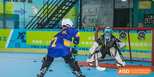 A young athlete in a blue hockey jersey with the number 7 takes a shot on a goalie during practice at Beijing International Bilingual Academy Guiyang.