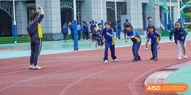 A student in a blue tracksuit prepares to run a race on the red outdoor track during sports day at Beijing International Bilingual Academy Guiyang.