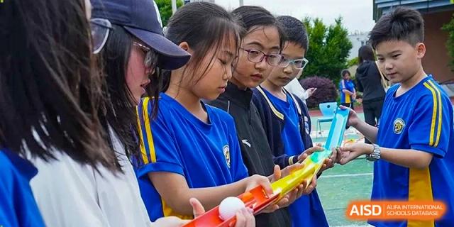 Students work together to balance a ball on a yellow track during a team-building coordination game at Beijing International Bilingual Academy Guiyang.