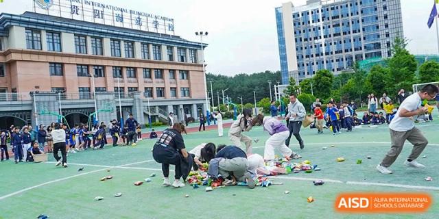 Students and staff gather around a large pile of colorful snacks during an outdoor celebration at Beijing International Bilingual Academy Guiyang.