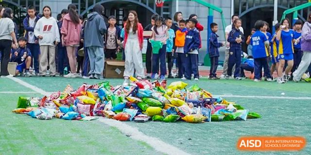 A pile of colorful snack bags sits on the grass as students wait to participate in a school game at Beijing International Bilingual Academy Guiyang.