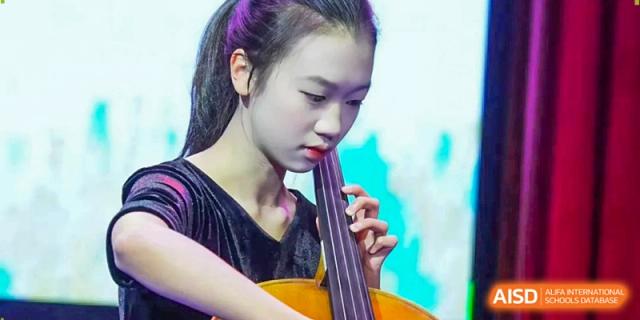 A young musician intensely focuses on her cello performance during a formal recital at Beijing International Bilingual Academy Guiyang.