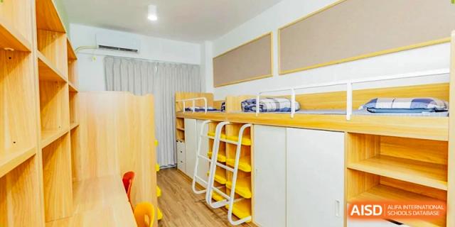 A student dormitory room featuring sturdy wooden bunk beds and organized storage cabinets at Benenden Bilingual School Guangzhou