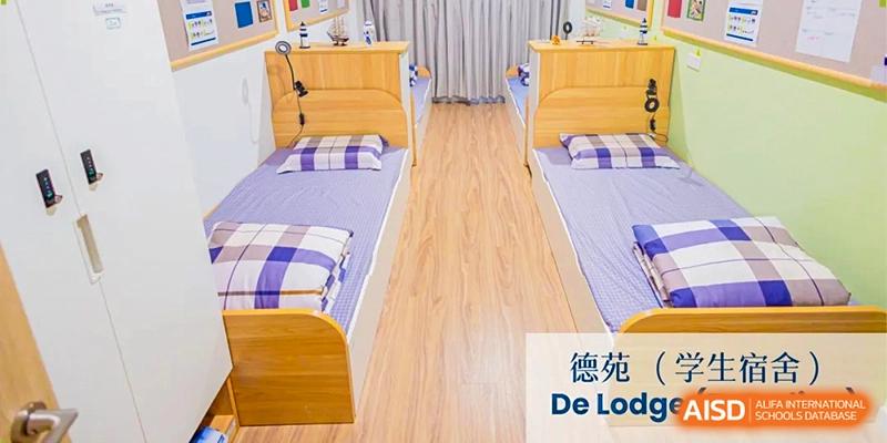 Two neatly arranged single beds with blue and white checkered linens in a bright student dormitory room at Benenden Bilingual School Guangzhou