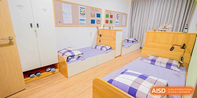 A view of multiple comfortable beds with checkered bedding in a clean and well-lit student housing facility at Benenden Bilingual School Guangzhou