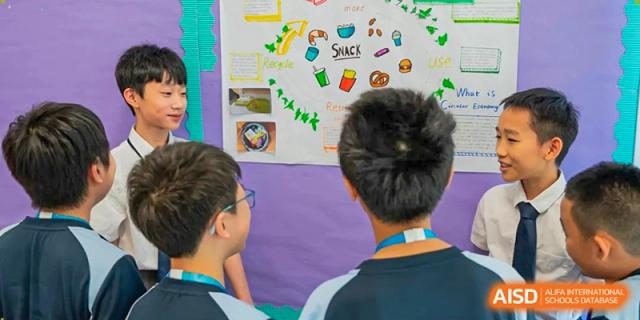 Two students stand together in a hallway looking at a colorful wall display featuring student projects at Benenden Bilingual School Guangzhou
