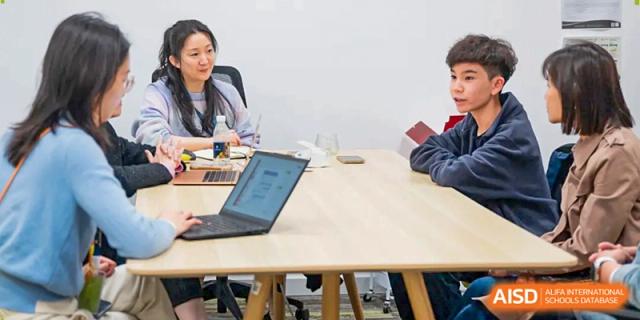 A teacher and student sit at a light wooden table during a focused one-on-one academic session at Benenden Bilingual School Guangzhou