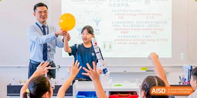 A student holds a yellow balloon while participating in a physics experiment about energy and motion at Benenden Bilingual School Guangzhou