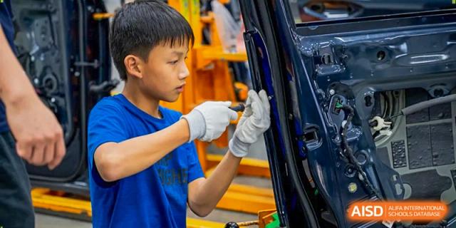 A young student wearing white protective gloves works on a technical project in a school workshop at Benenden Bilingual School Guangzhou