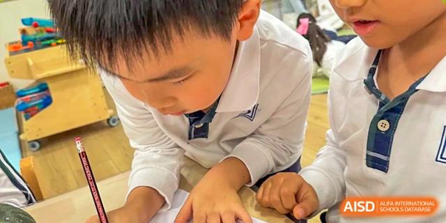 A young student focuses intently while working on a creative project at a classroom desk at Benenden Bilingual School Guangzhou