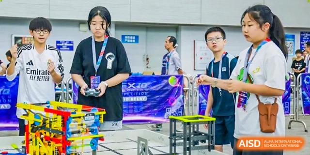 Students stand near a colorful banner while participating in a school event or competition in a large hall at Benenden Bilingual School Guangzhou