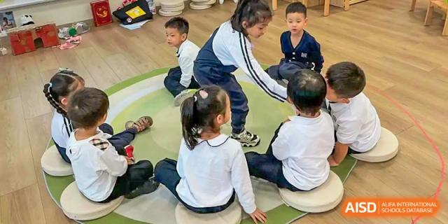 Students sit in a circle on a green rug for a collaborative group activity led by their teacher at Benenden Bilingual School Guangzhou